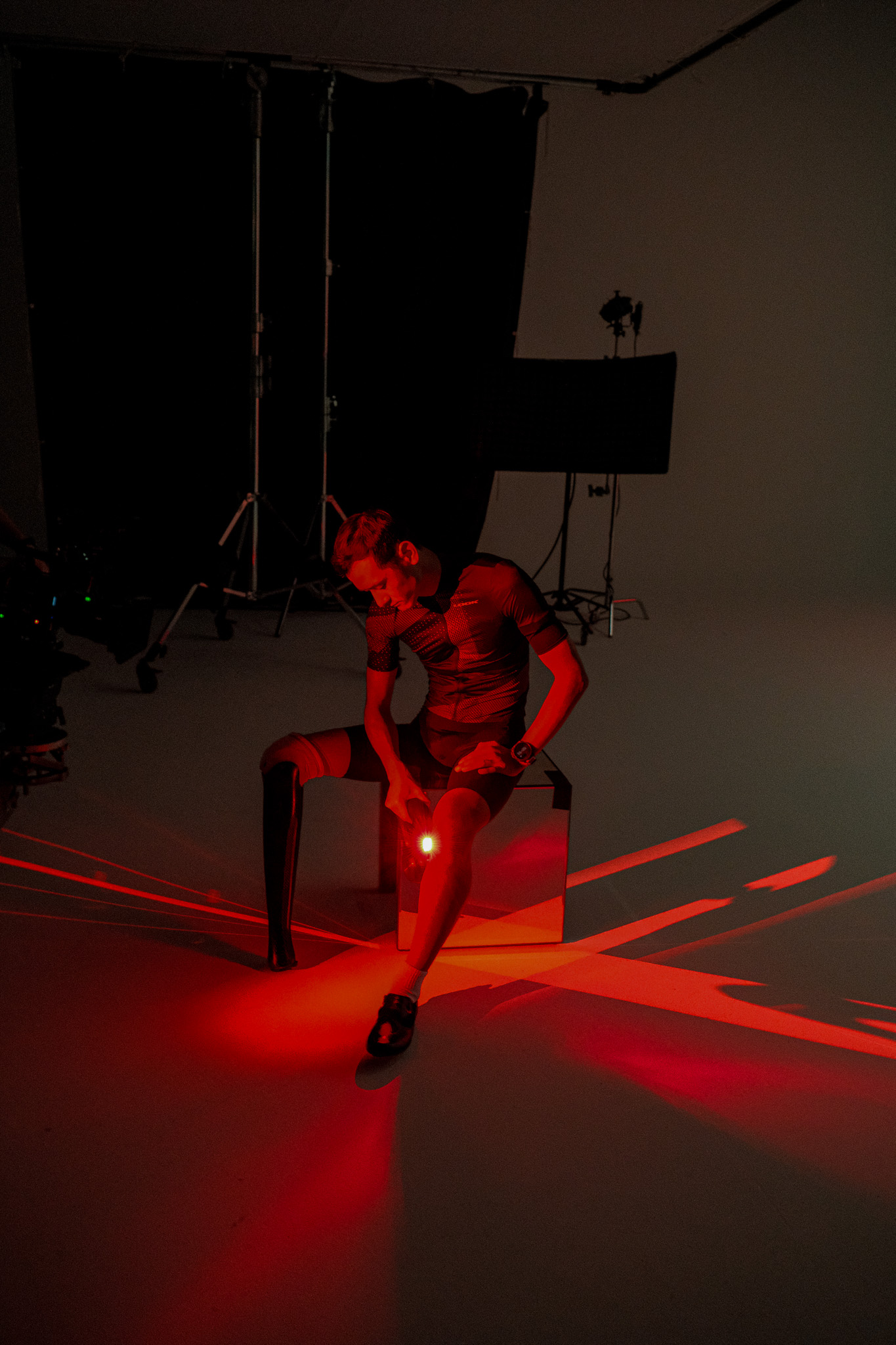 Kai bathed in red light working a Theragun into his knee