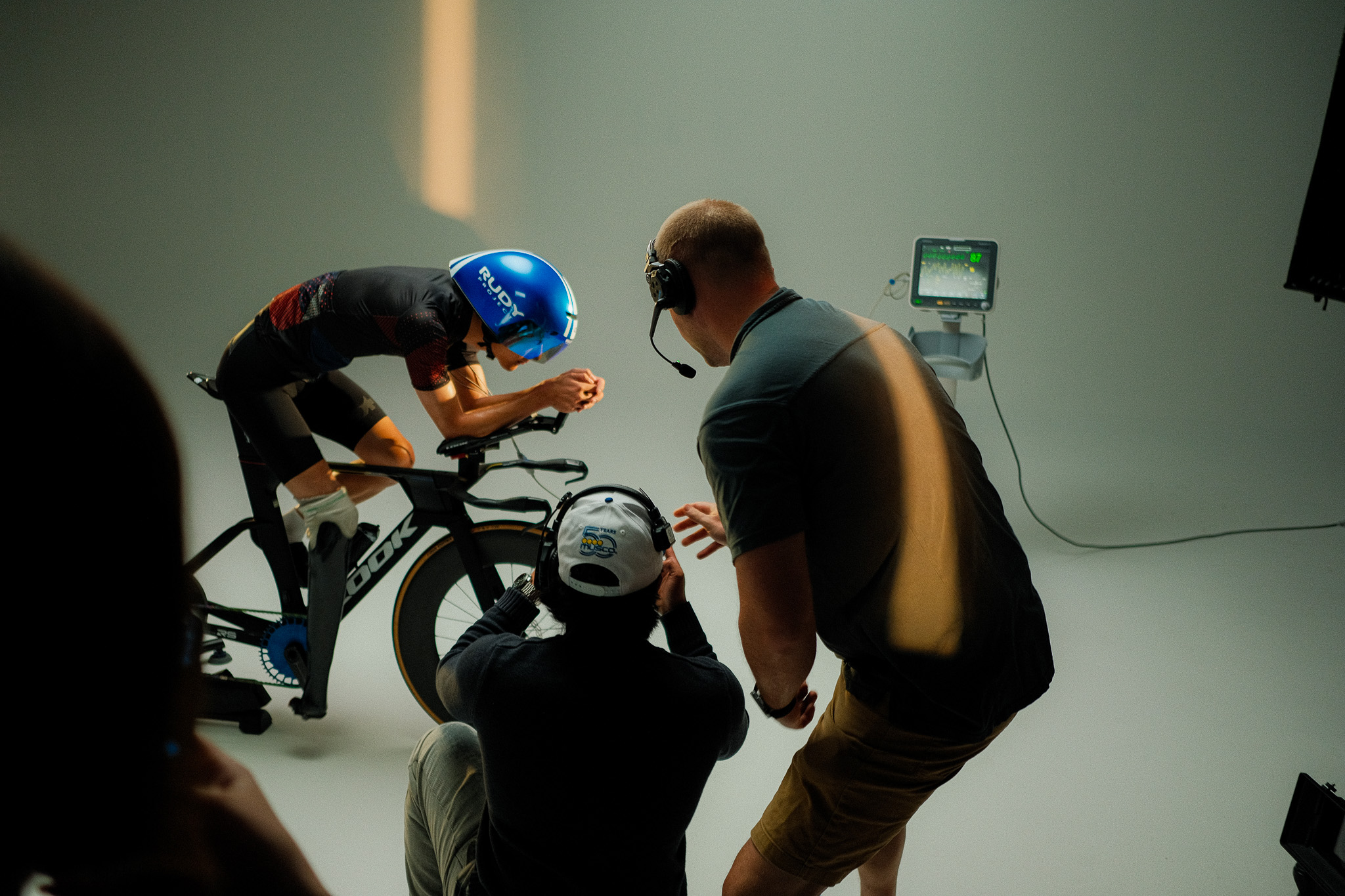 Kai on the time trial bike as the director films on a phone and the AD watches over a heart rate monitor