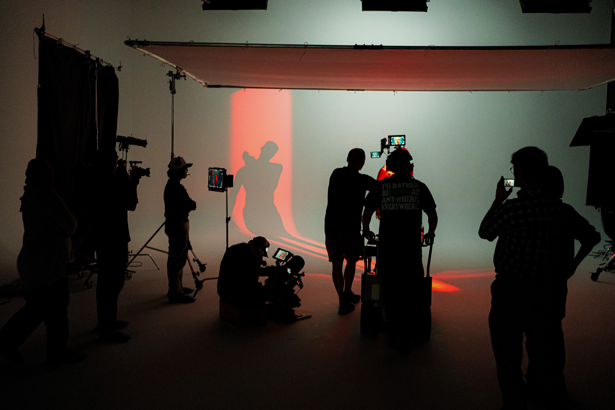 Crew in silhouette as an athlete's shadow is cast in red light on the cyc wall