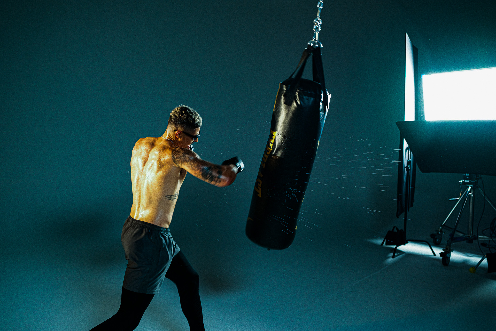 Jordan landing a punch on the heavy bag as sweat sprays off the impact