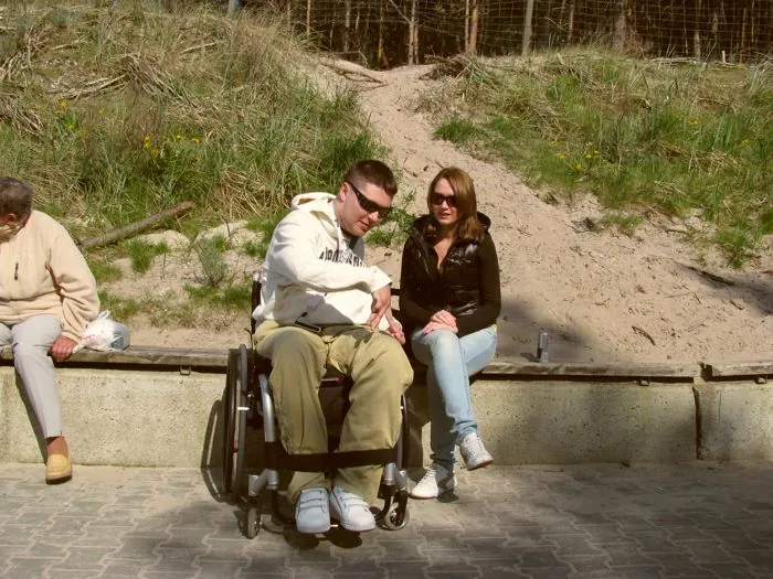 Paweł im Rollstuhl mit Freundin an den Dünen