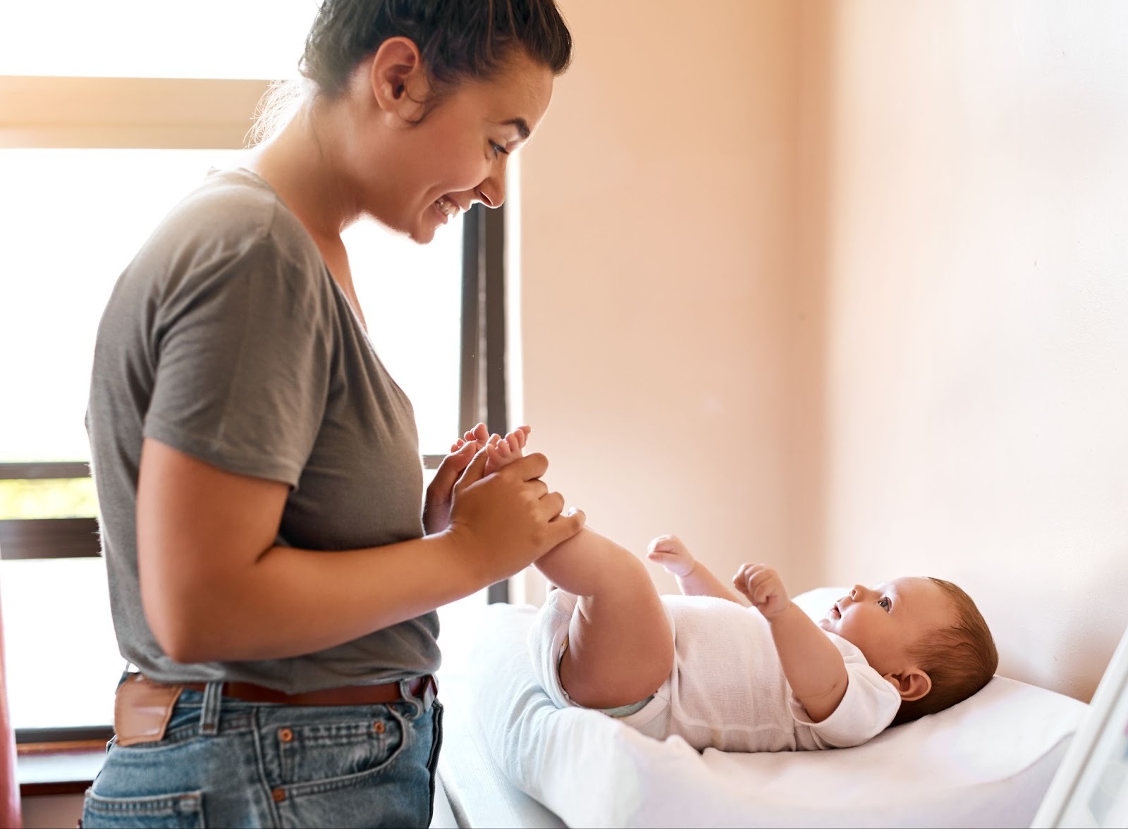 Parent caring for a newborn on a changing table, reflecting the mental load and shifting roles after baby arrives.