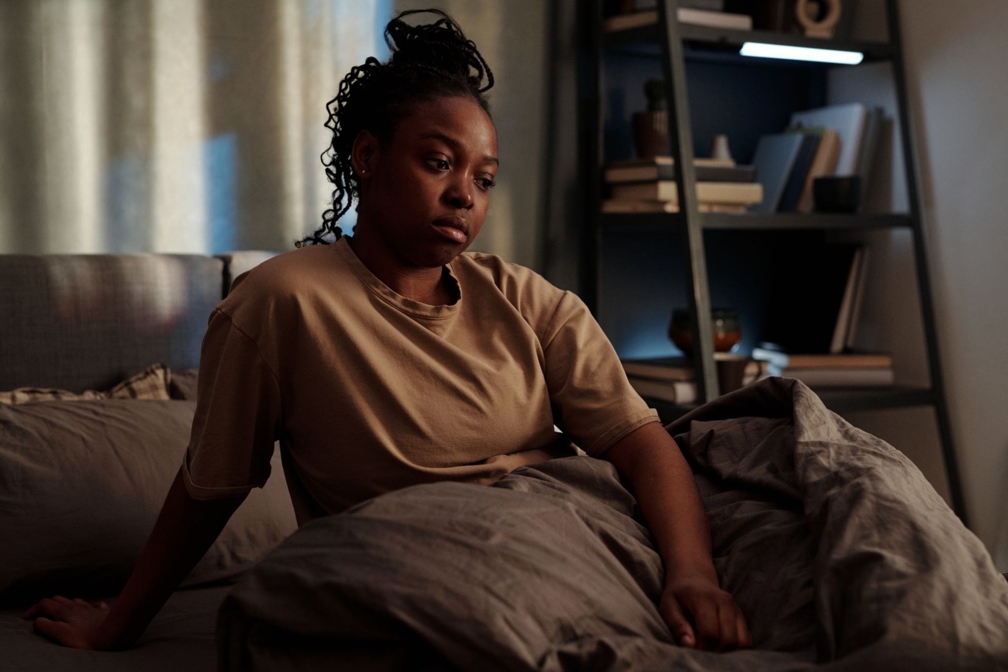 Woman awake at night looking overwhelmed in bed, illustrating the stress of insomnia and infertility and how disrupted sleep and fertility concerns can affect emotional well-being.