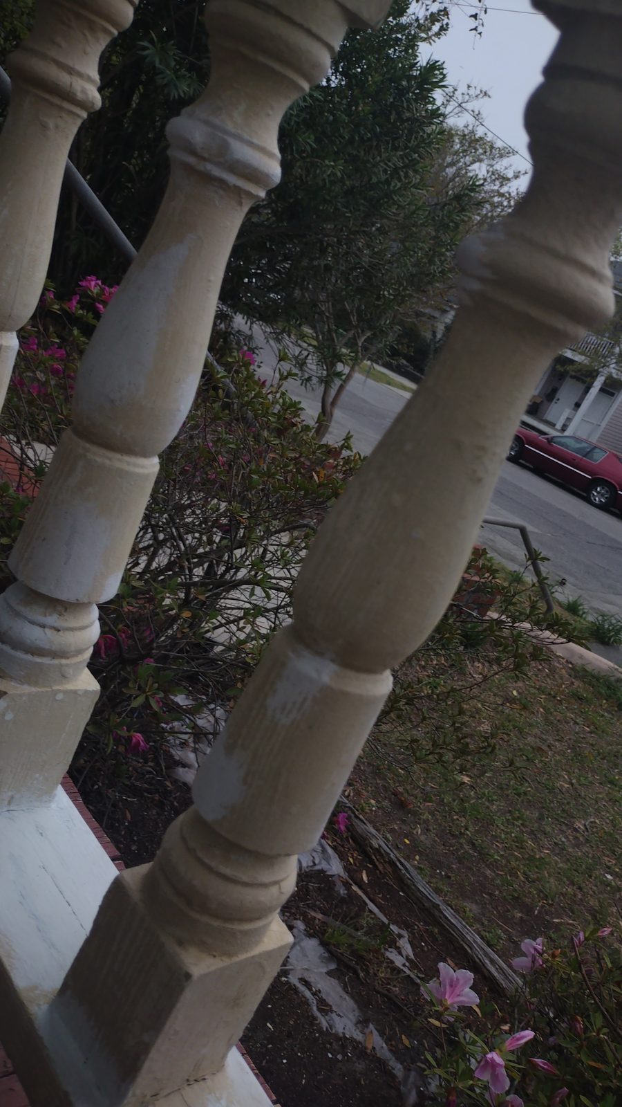 Close-up of turned porch balusters with garden plantings behind