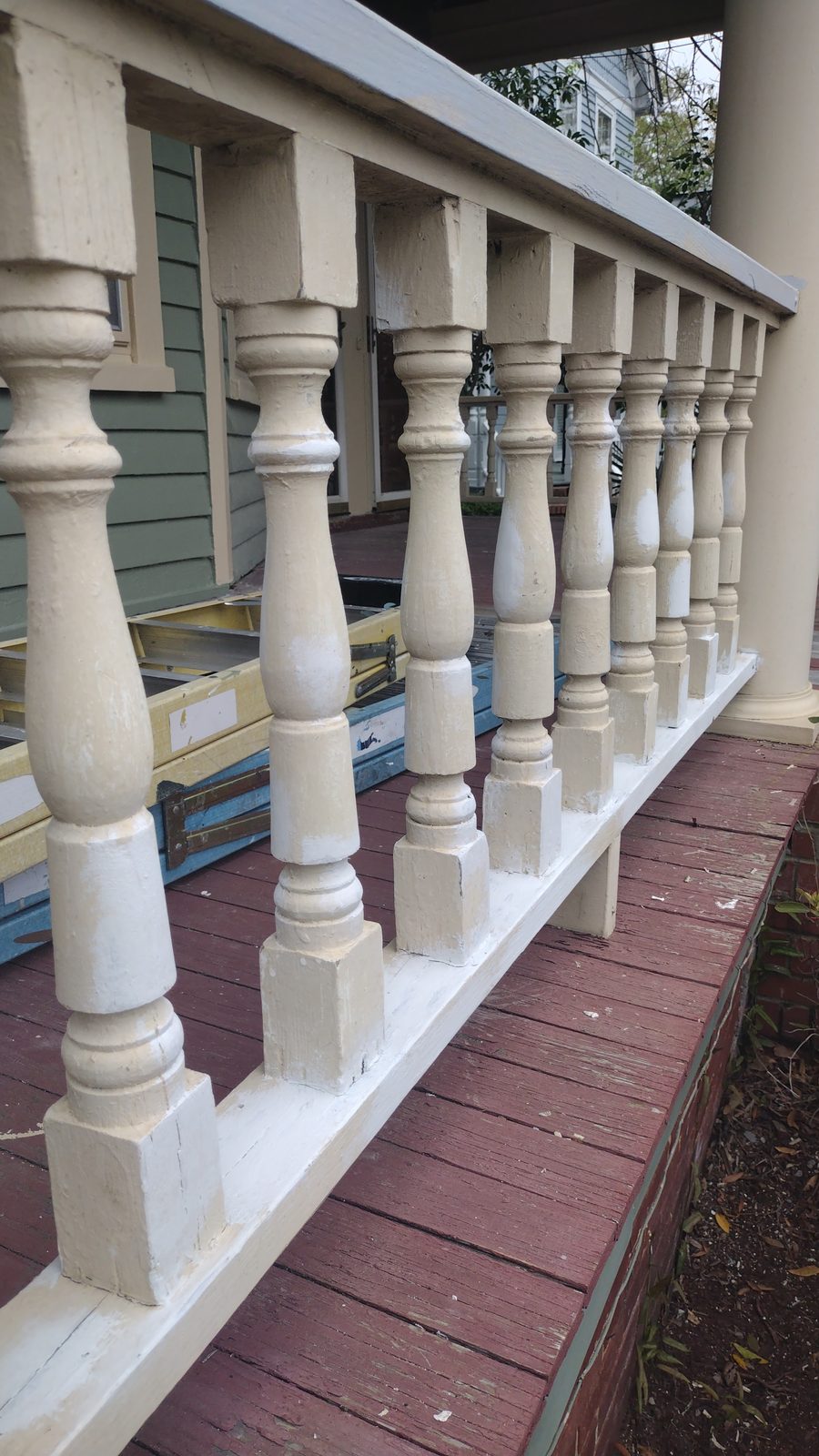 Row of hand-painted white turned balusters along a restored porch railing