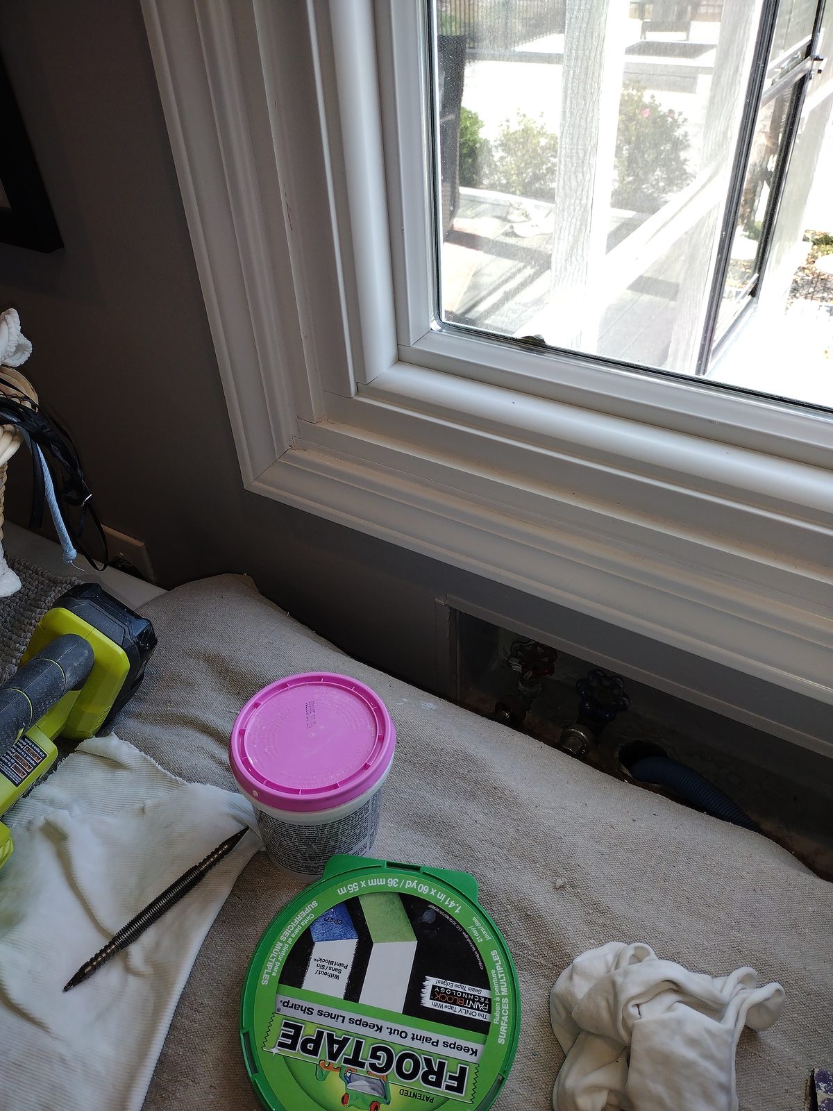 Window trim being prepped and painted, with tape and materials on the sill