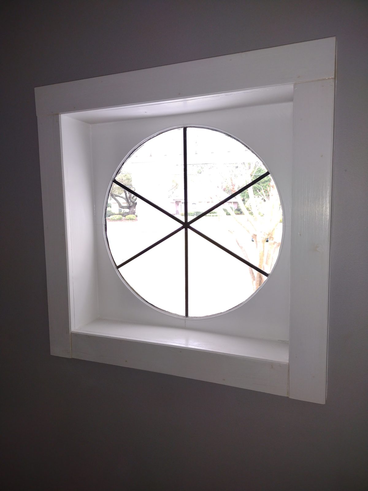 Restored round porthole window set in painted white trim