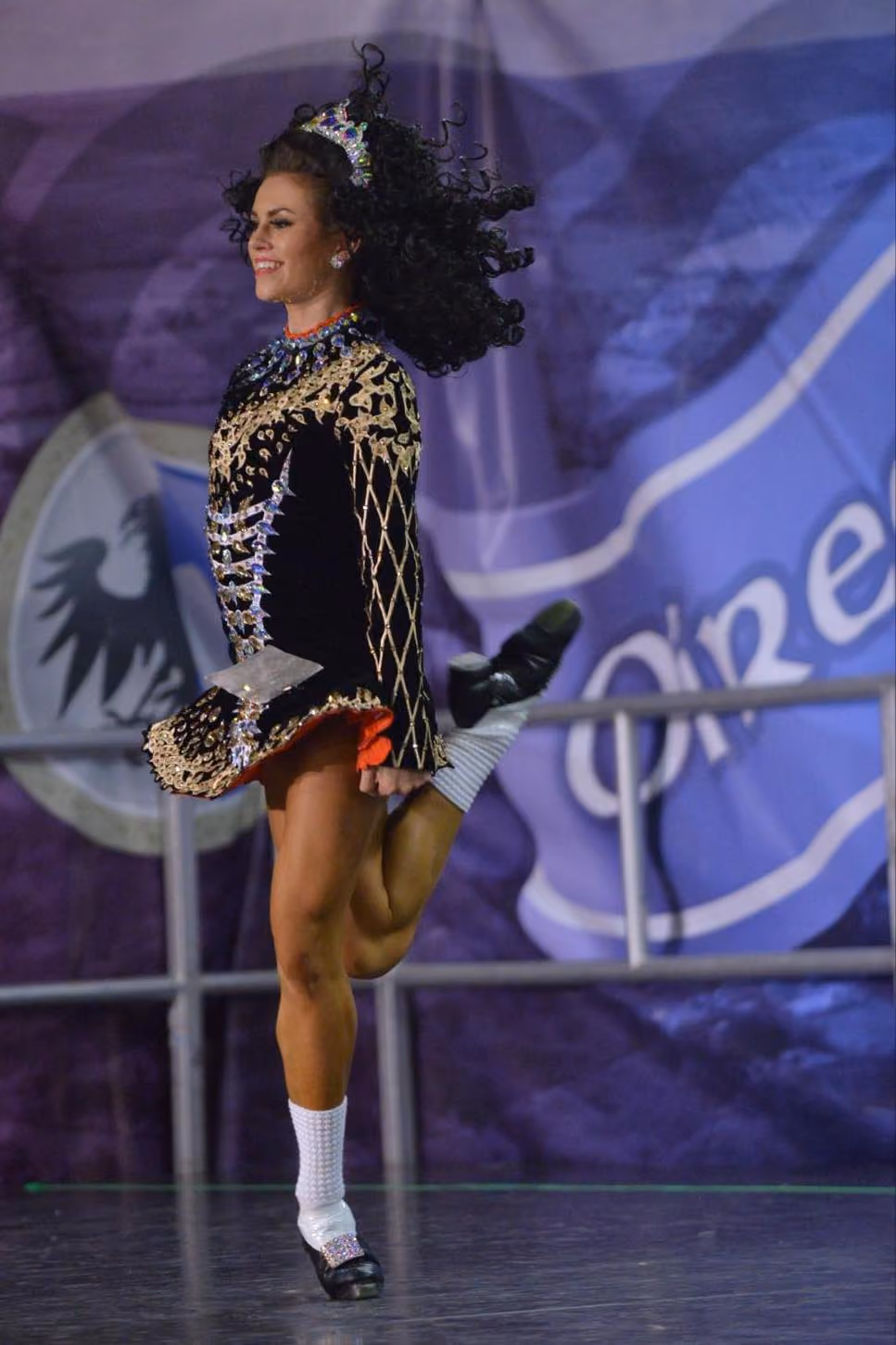 A world champion irish dancer on stage mid dance.