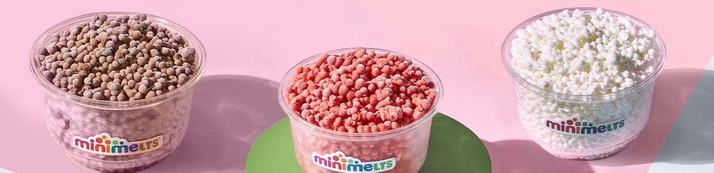 Trois gobelets Mini Melts — chocolat, fraise et vanille — sur fond rose