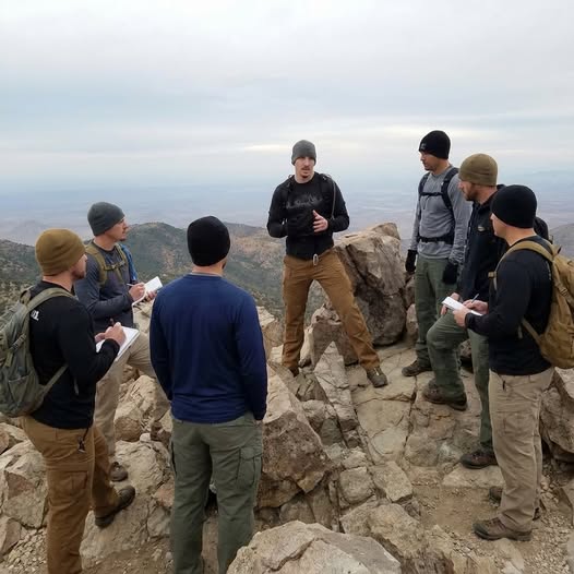 Mark speaking to a group of men gathered on a mountaintop