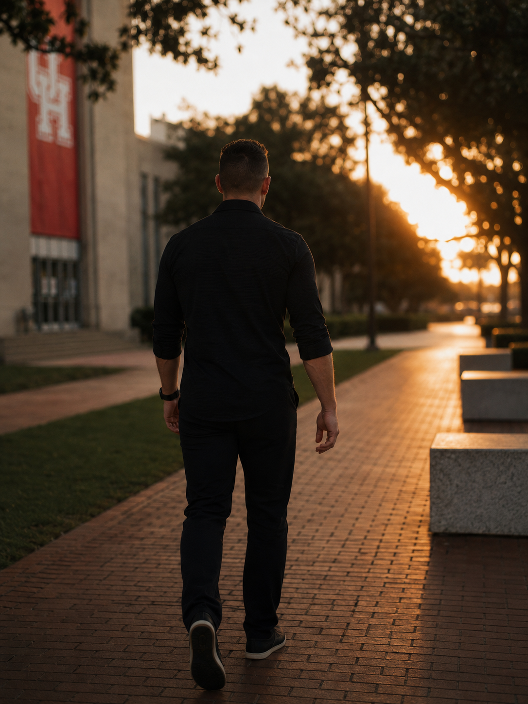 Mark walking alone across the University of Houston campus at sunset