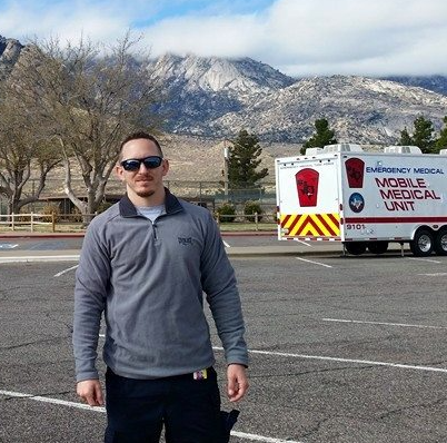 Mark standing in front of mobile medical unit emergency vehicles with mountains in the background