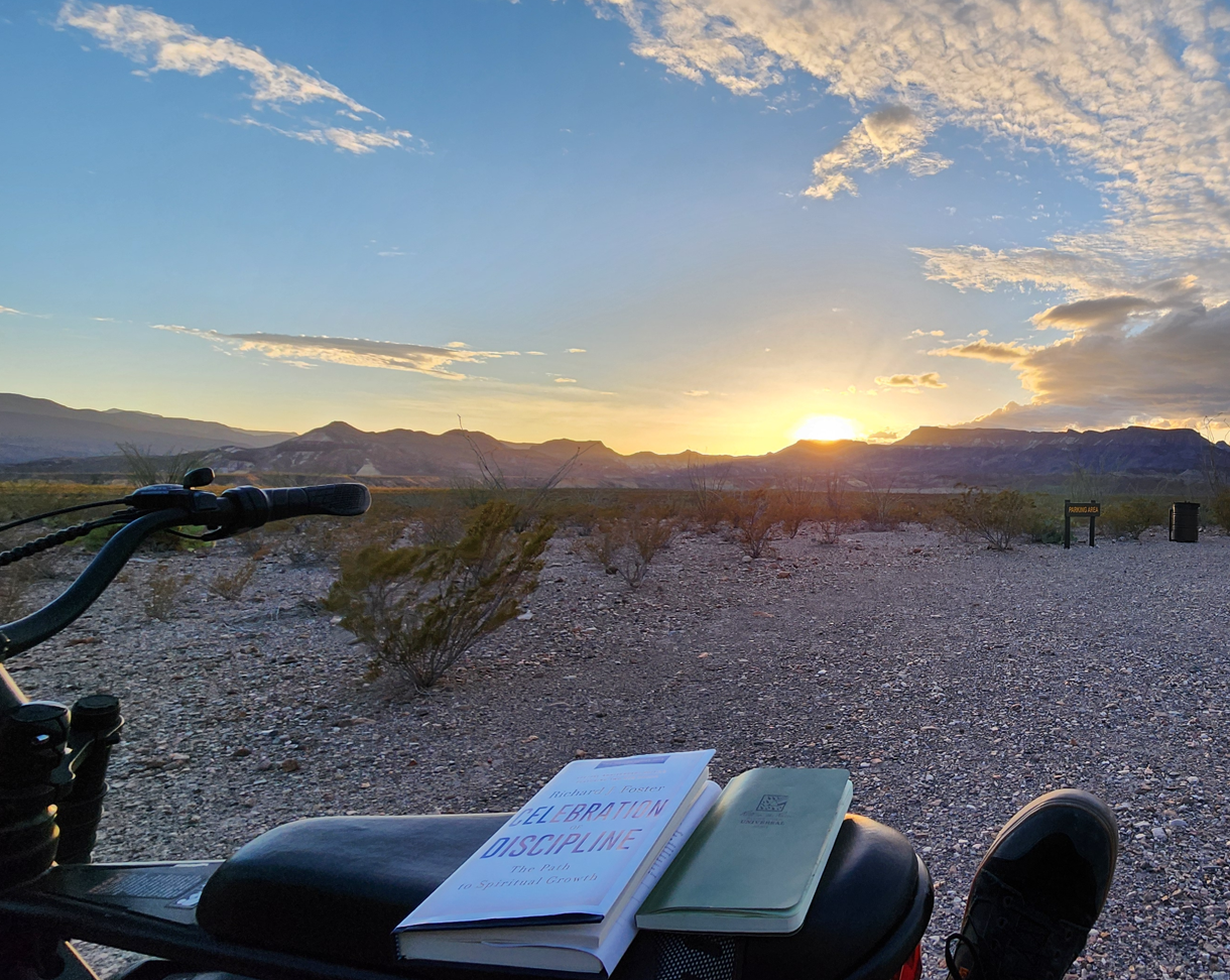 Man sitting on a mountain peak at sunset