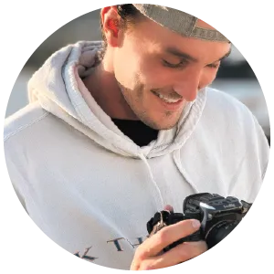 Brady Kingma, Founder of Seek The Kingdom LLC profile picture. This image show Brady Kingma smiling while looking down into the camera behind the scenes of a photoshoot promoting the Kingdom Seeker Hooded Sweatshirt.
