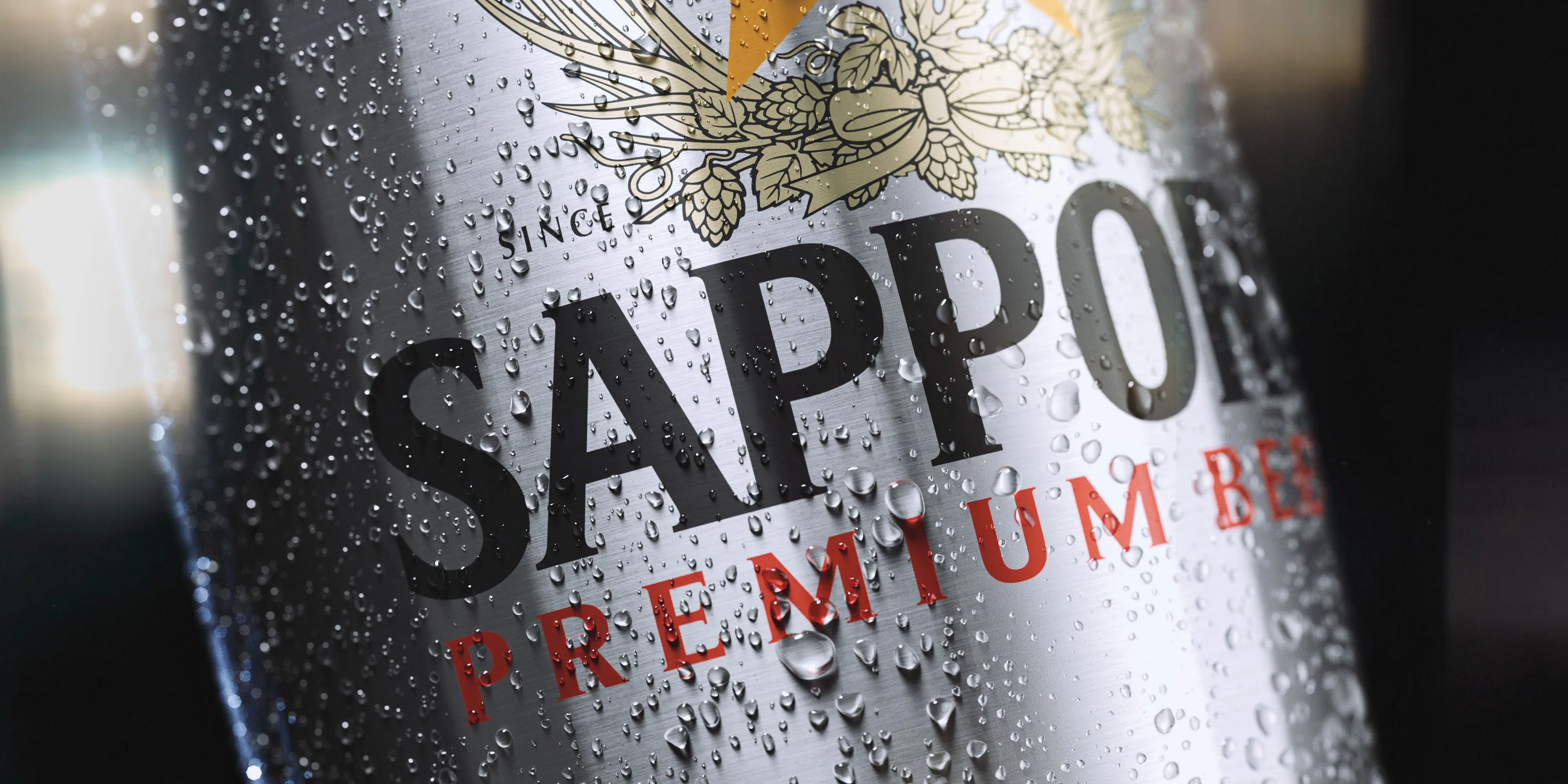 Macro visualization of a condensation-covered Sapporo Premium Beer can with crisp metallic detail.