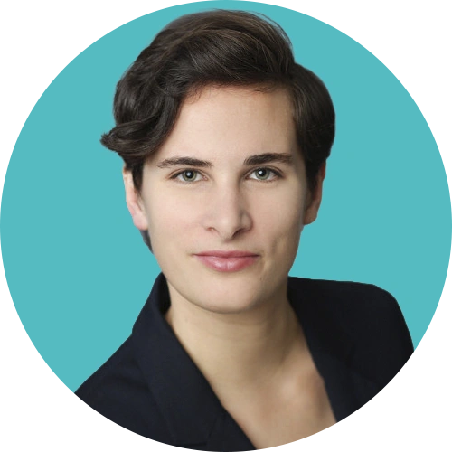 Professional headshot of a young person with short dark hair, wearing a black blazer against a teal background.