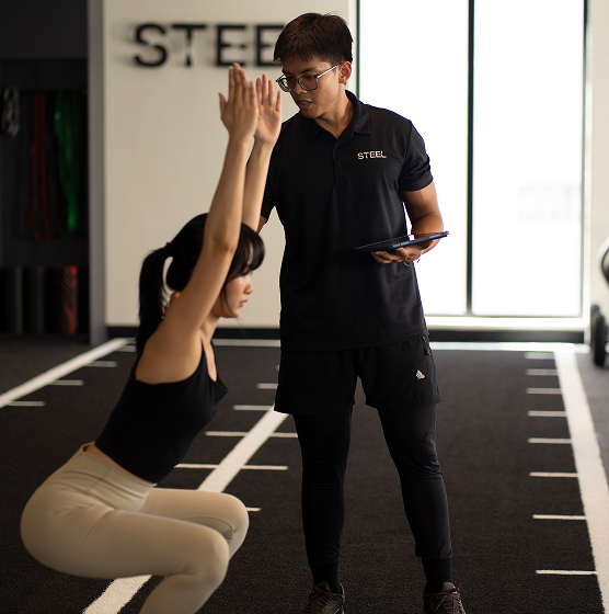 STEEL Saigon elite coach consulting on iPad, showcasing luxury fitness with Eleiko for personal training