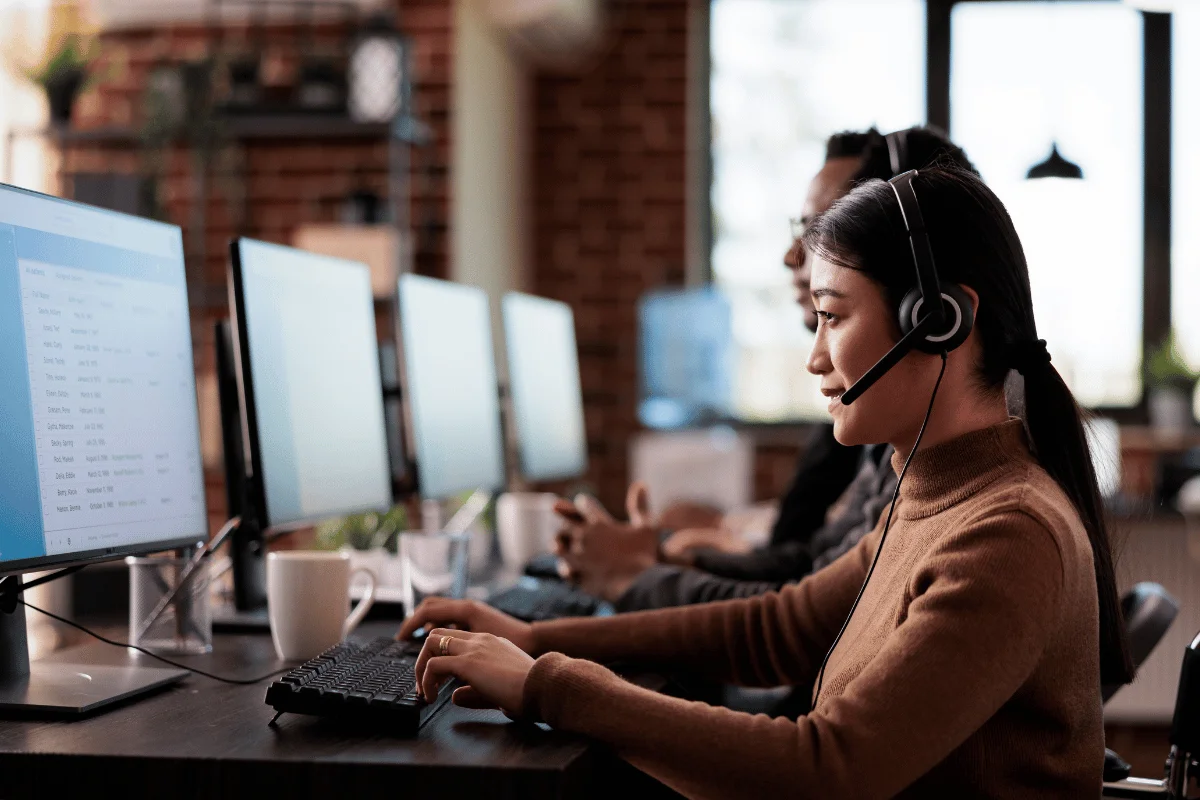 Customer support agent smiling while working on computer.