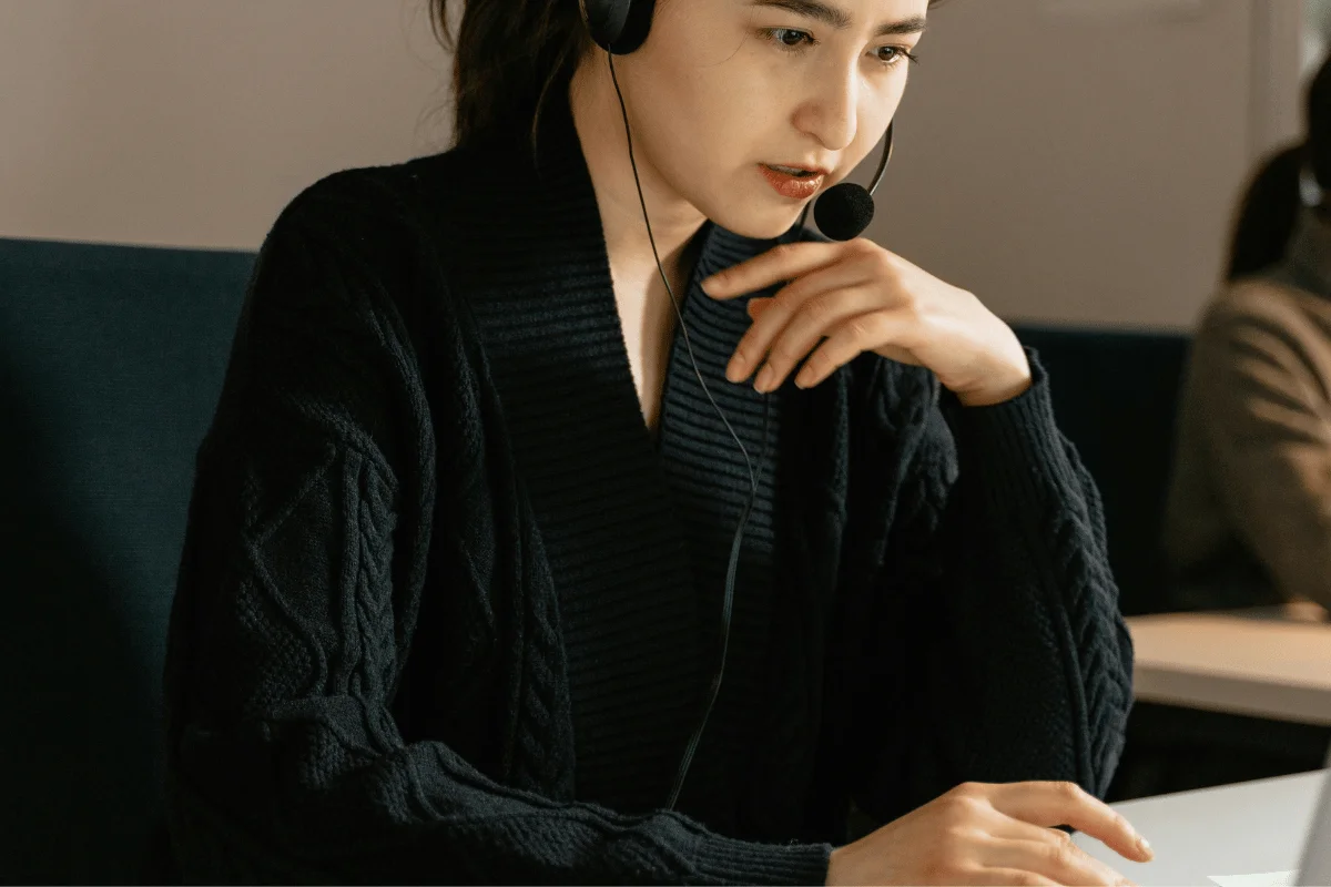 Woman wearing a headset providing customer support at her desk in a modern office environment.
