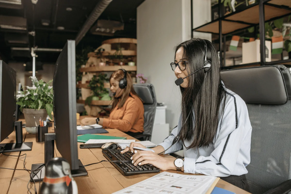Call center agent typing at desk with headset on.