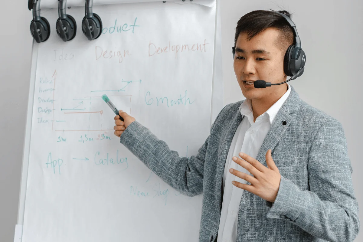 Business professional giving a product roadmap presentation with headset and whiteboard.