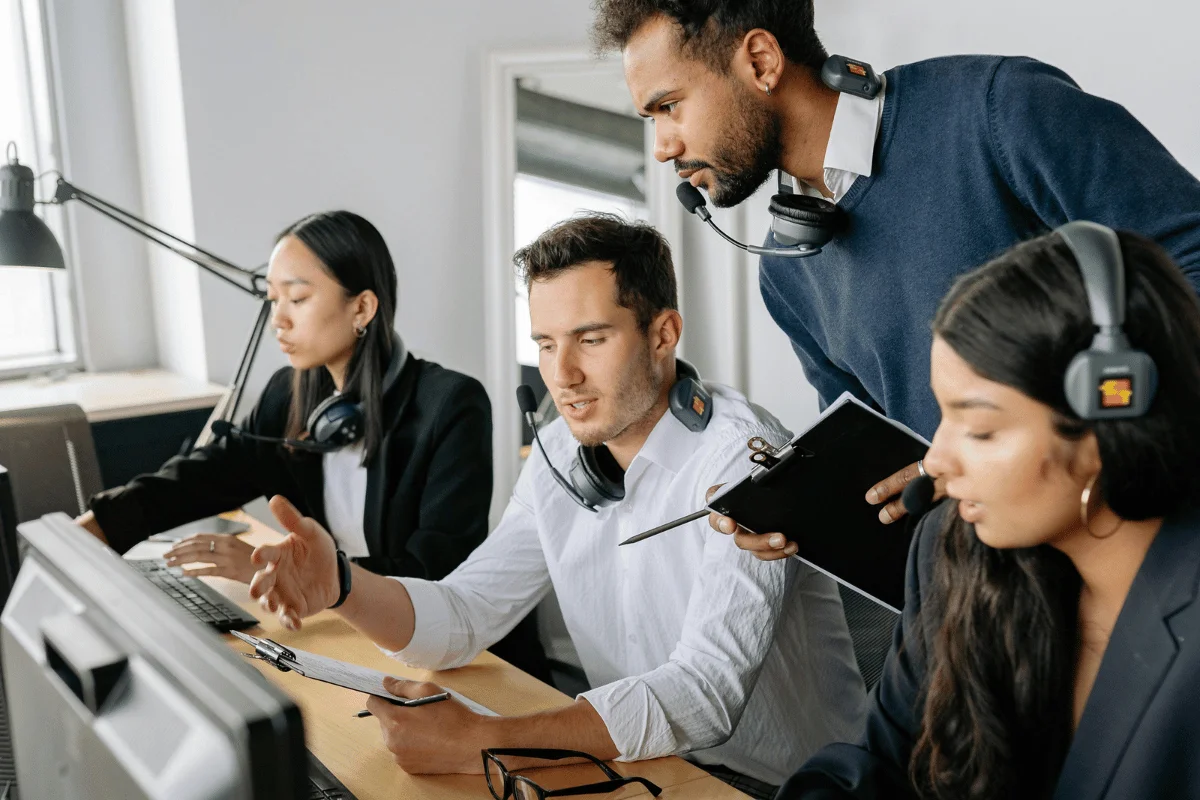Diverse team of customer support agents collaborating at computers.