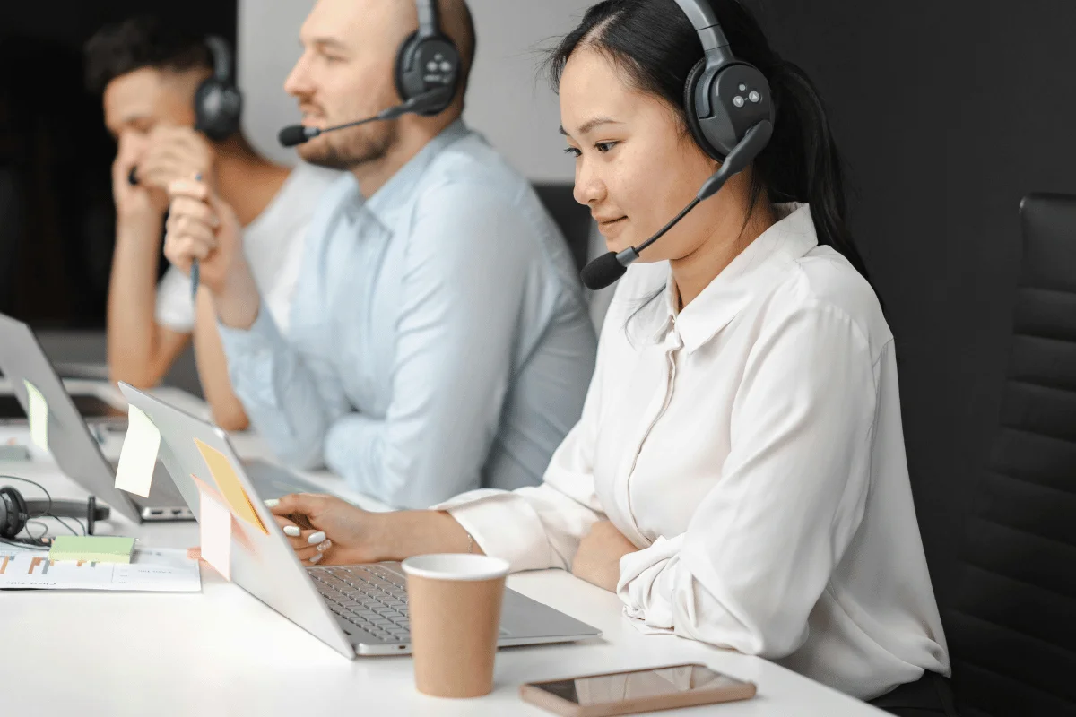 Woman in headset working on laptop at customer service office.