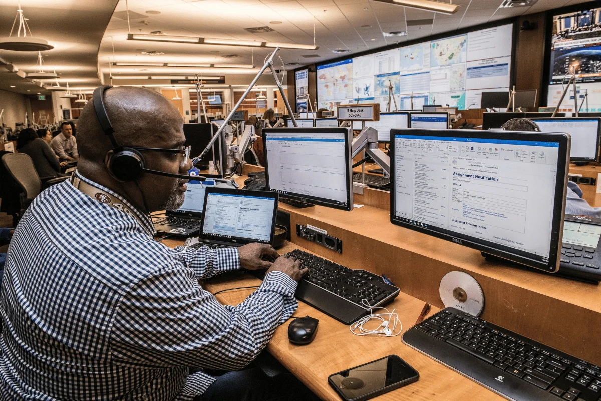 IT professional monitoring multiple computer screens at a help desk.