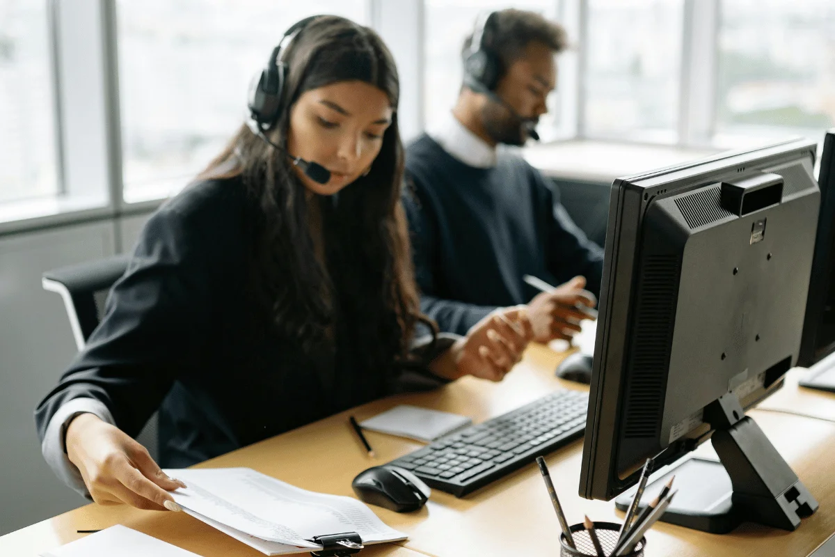 Call center agents with headsets assisting customers on computer systems.