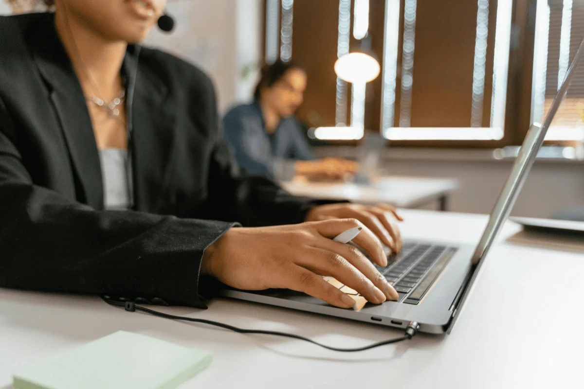 Customer service agent typing on laptop with headset in office.