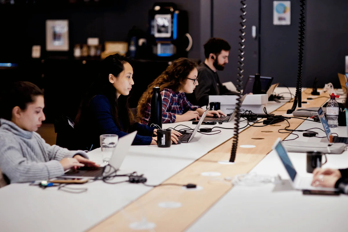 Employees working on laptops in a modern coworking office space.