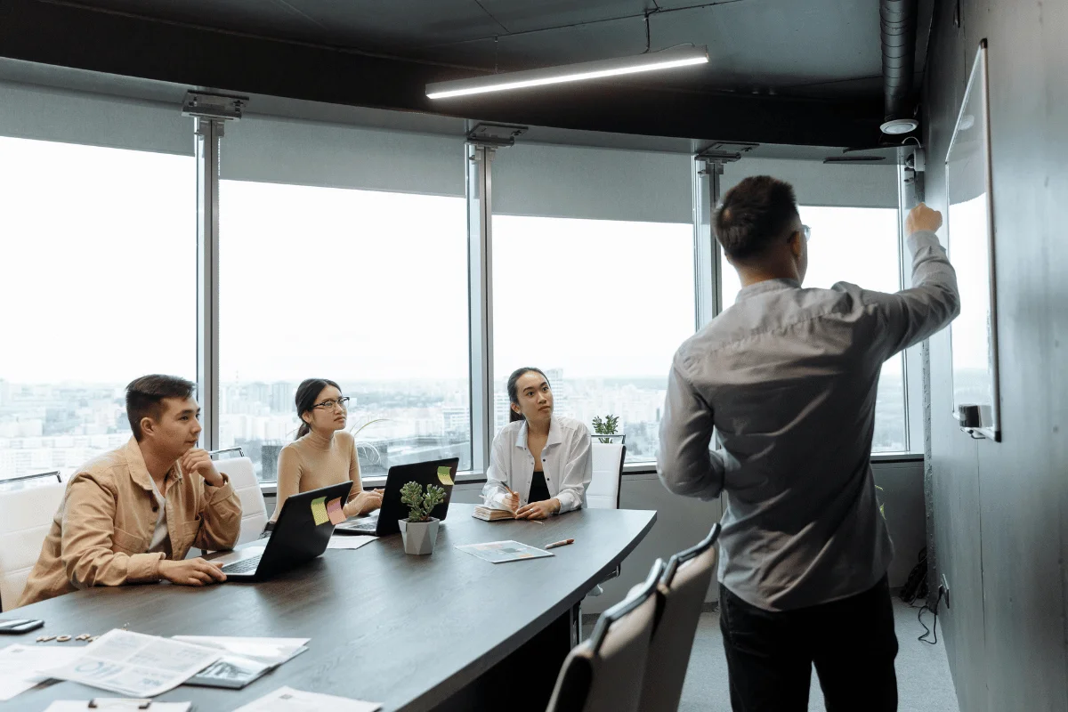 Man presenting strategy on whiteboard during office meeting.