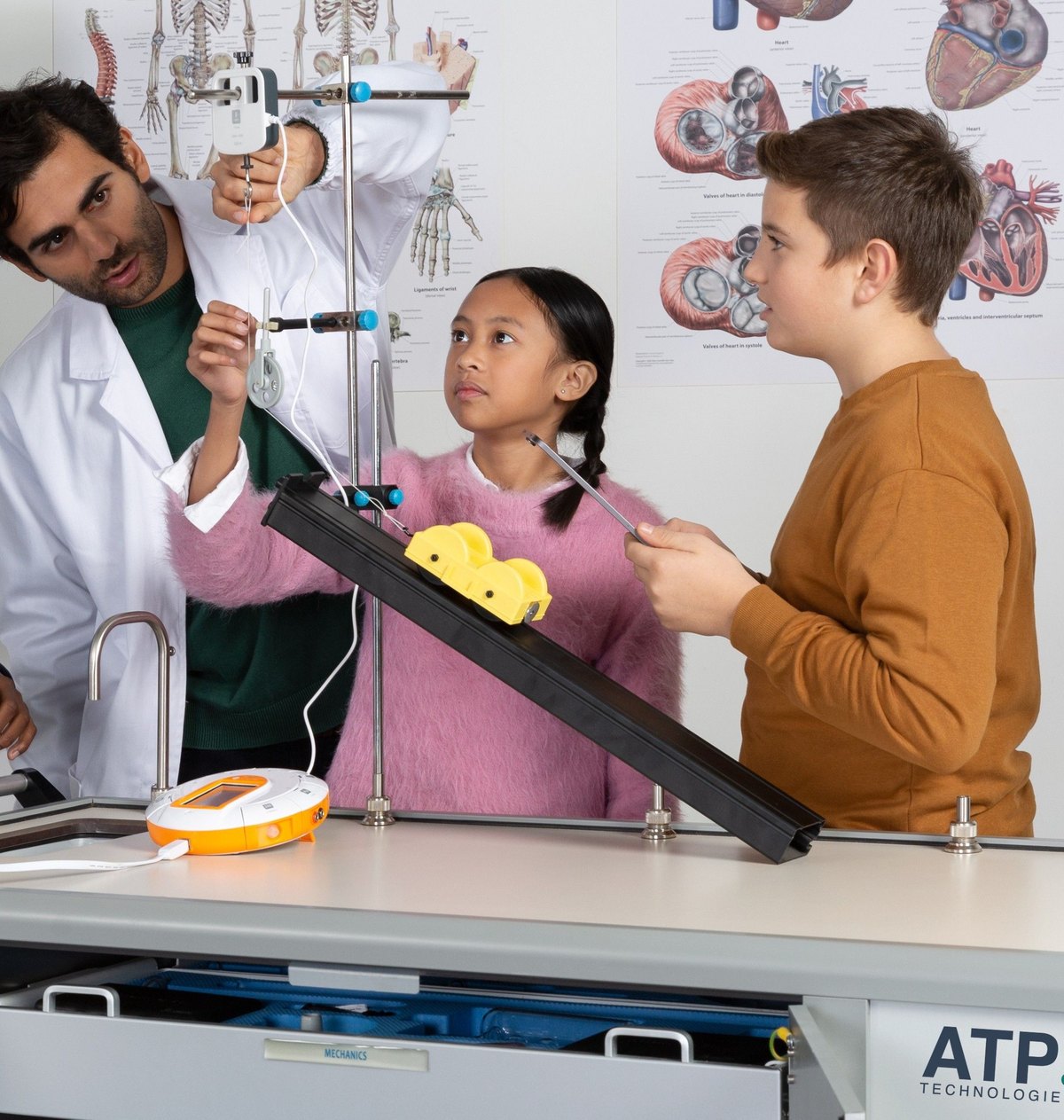 A teacher and two students setting up a pulley and dynamics track on the ATP Mobile Lab