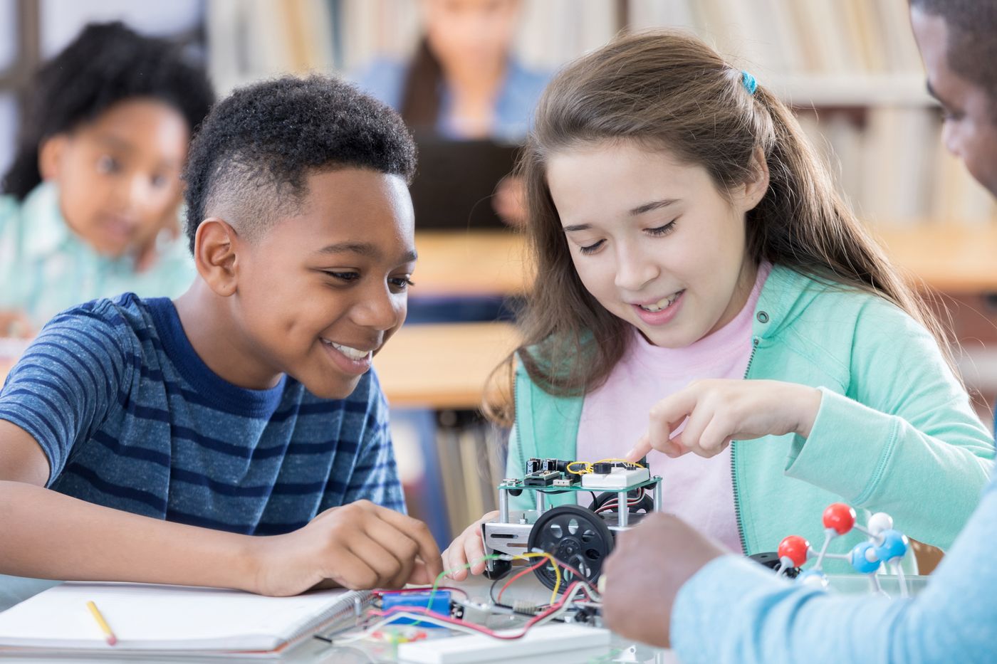 Deux élèves en train d'assembler un kit de robotique sur roues pendant un cours d'électronique