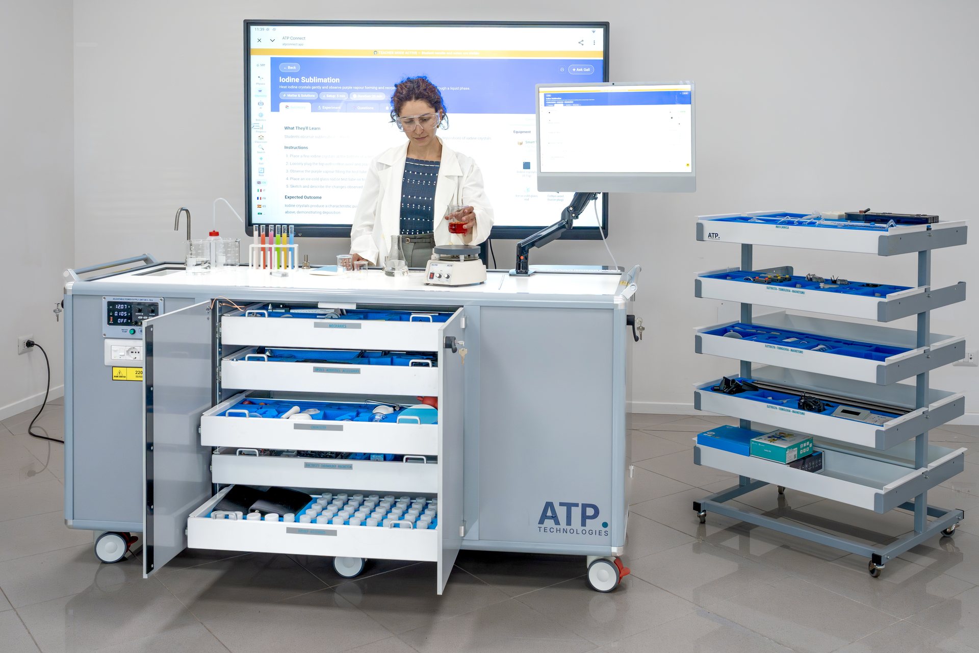مختبر «ATP Volta» العلمي المتنقل مع أدراج المعدات مفتوحة، ومعلم يُجري تجربة بتوجيه من ATP Connect