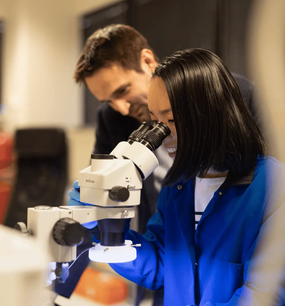 Man and women standing next to microscope