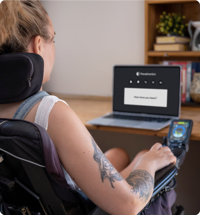 Person sitting in assistance chair with laptop in front of them