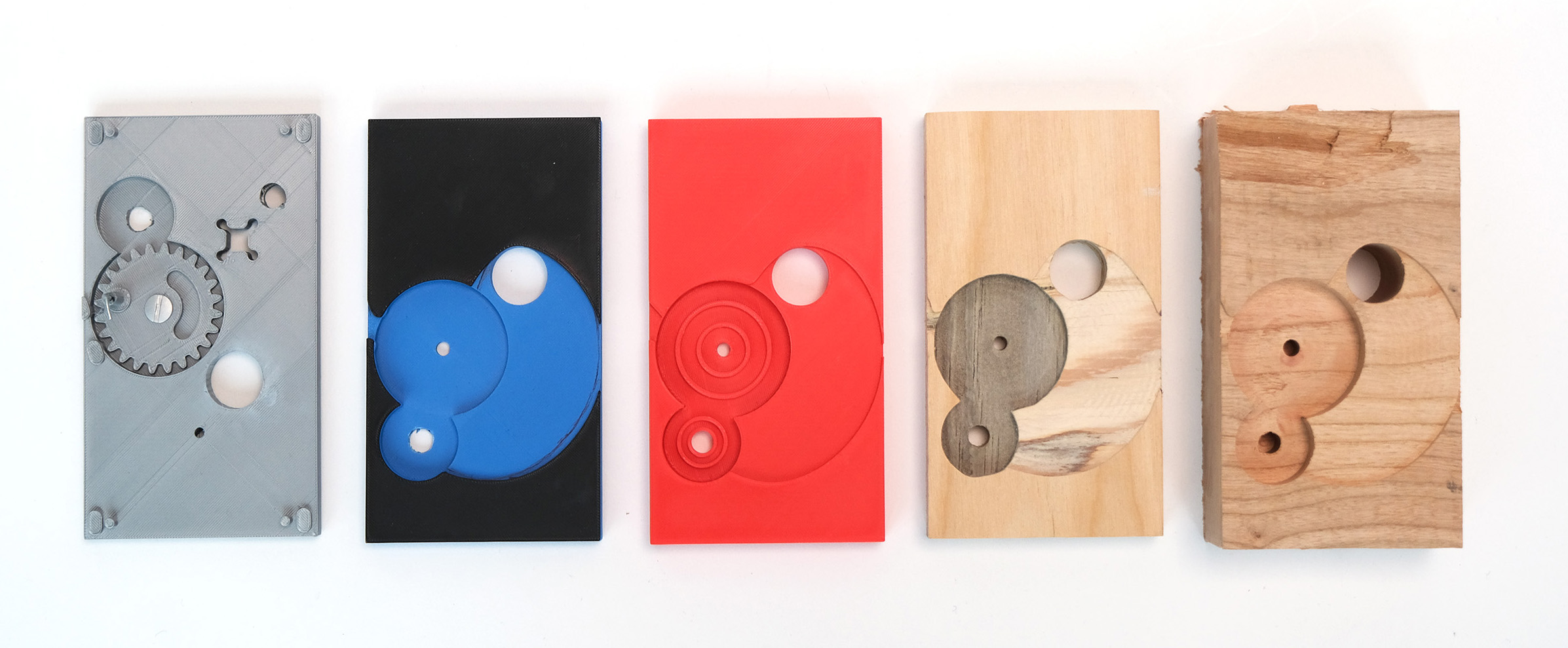 Photograph of the progression from 3D printed gear holder to wooden CNC cut one. 