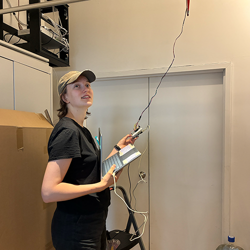 Me holding an Arduino and computer, connected to the bird sculpture hanging on the ceiling. 