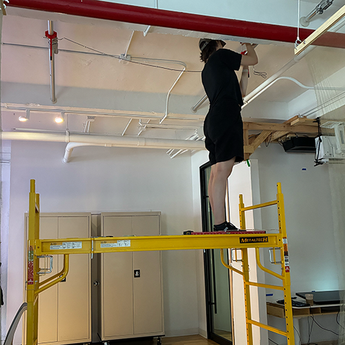 A photo of me standing on a scaffolding structure to hang something on the ceiling. 