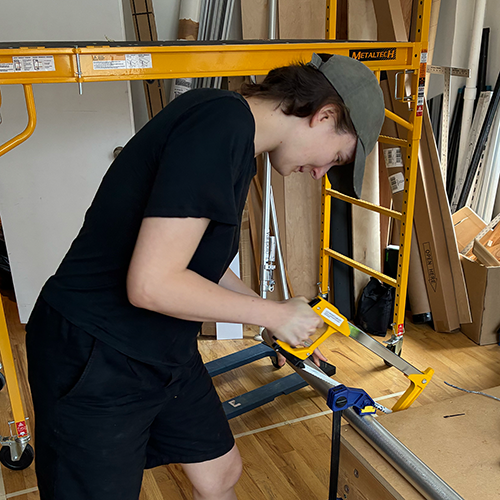 Photo of me sawing apart the Veripole on a table. 