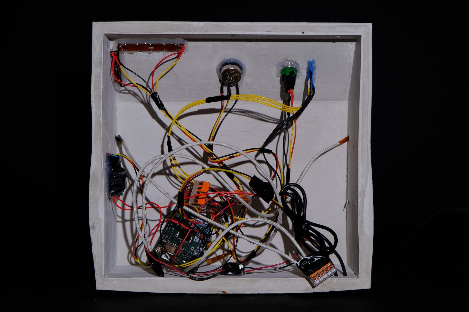 Inside view of a white electrical box with various connected wires, a circuit board, resistors, and connectors.