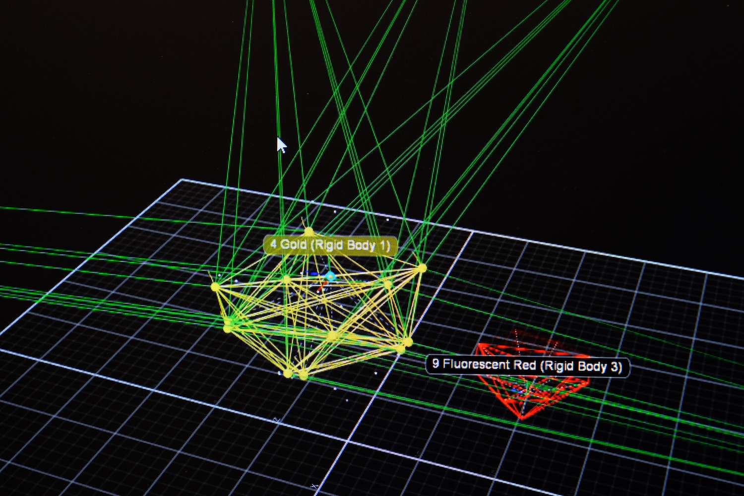 3D motion capture software showing yellow and red labeled rigid bodies with connecting lines on a grid.