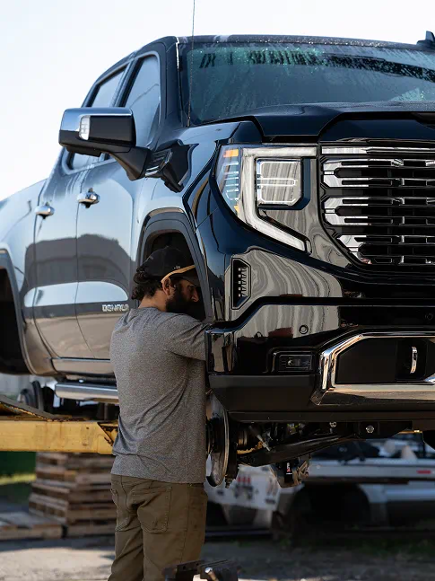 Technician working under a lifted GMC Sierra