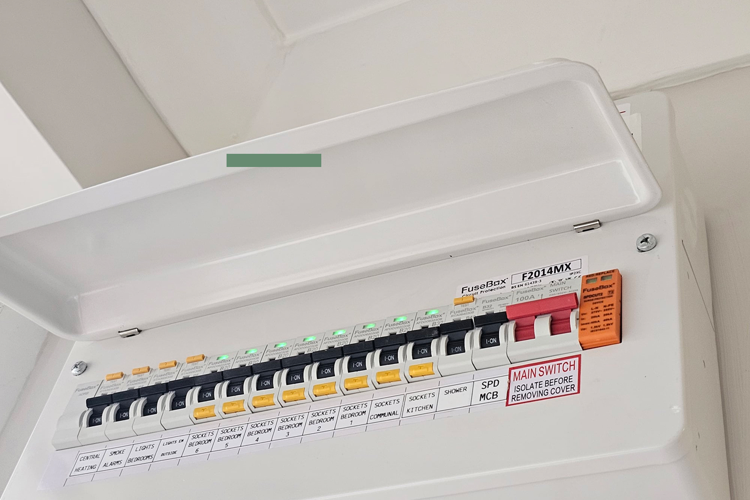 Electric fuse box with labelled circuit breakers for central heating, smoke alarms, lights, sockets in various rooms, kitchen, shower, and main switch.