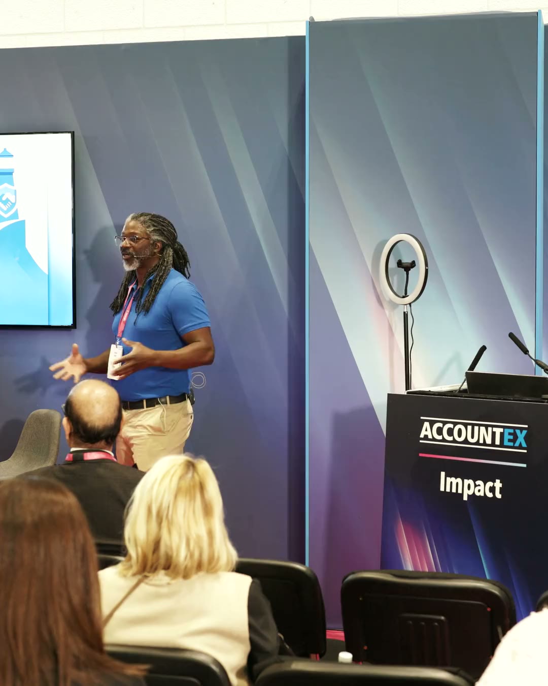 Kevan Smith speaking on stage at AccountEx to a seated audience.