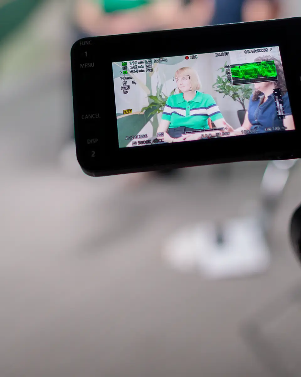 A camera monitor on set showing the We Are Brave founders being filmed.