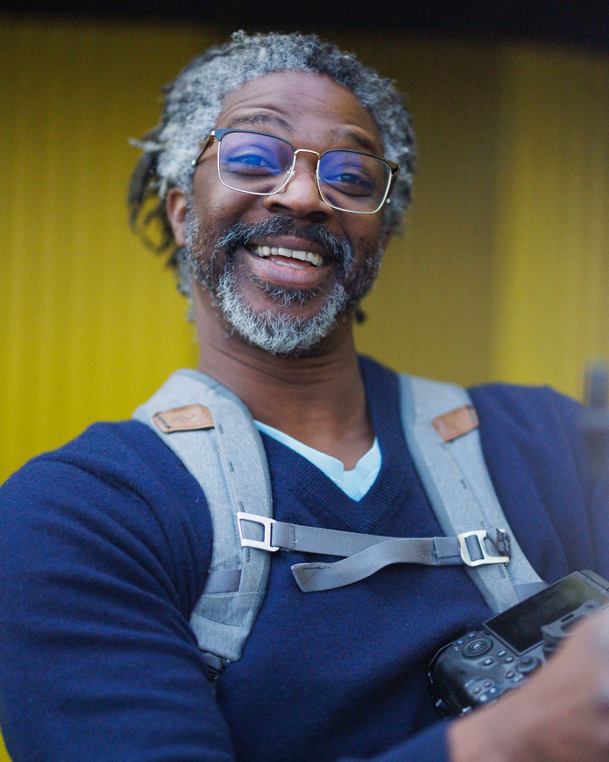 Kevan smiling at the camera with a camera on his harness and a light beside him, on the day of Jon's headshots, January 2024