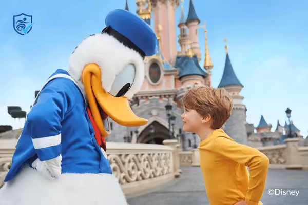 A young boy facing Donald Duck outside the Disneyland Paris castle