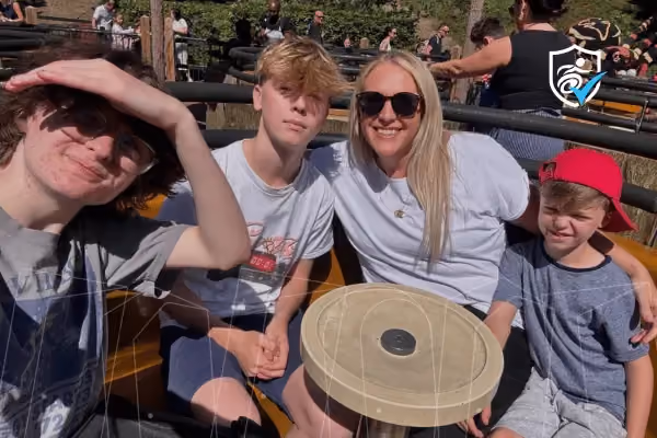 Photo of a woman and three children sitting around a table smiling at the camera.